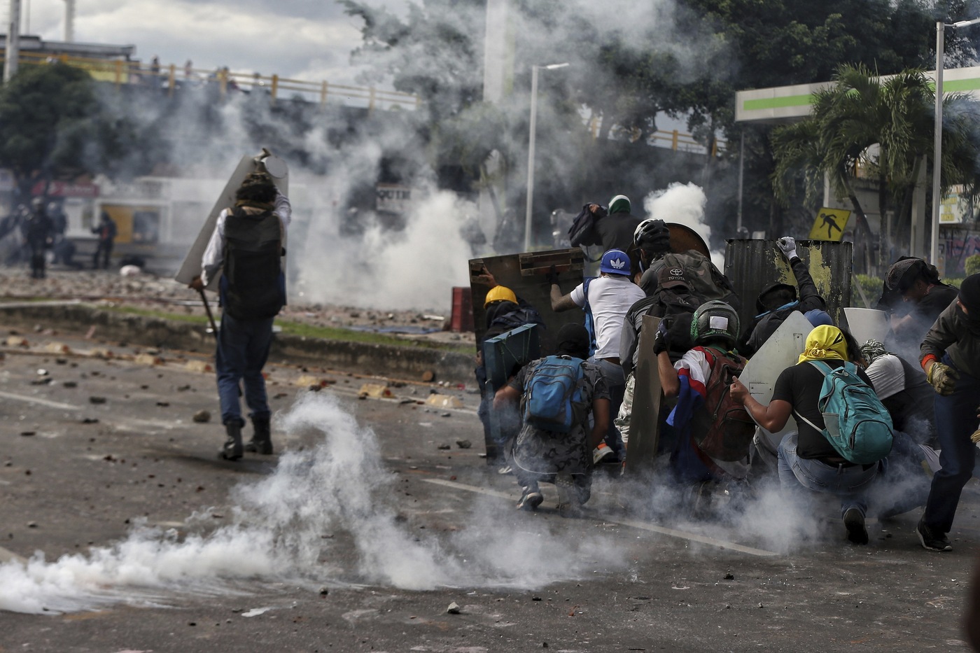 Protesters protect themselves with makeshift shields as they clash with the police during a national strike against tax reform in Cali, Colombia, Monday, May 3, 2021. Colombia's President Ivan Duque withdrew the government-proposed tax reform on Sunday. (AP Photo/Andres Gonzalez)