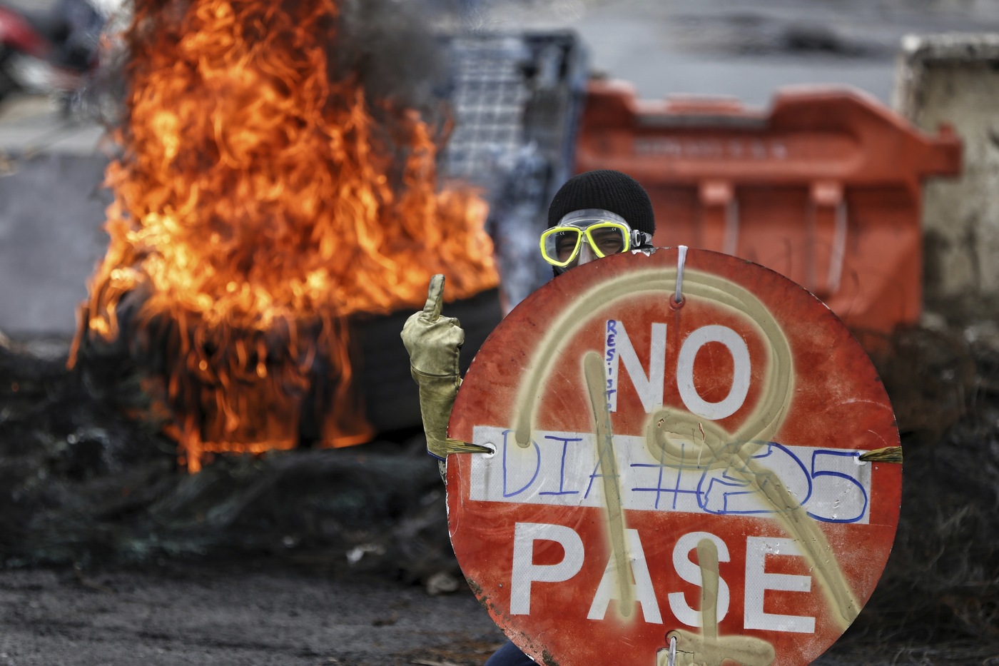 EDS NOTE: OBSCENITY - A protester protects himself with a traffic sign as he gestures obscenely at police during a national strike against tax reform in Cali, Colombia, Monday, May 3, 2021. Colombia's President Ivan Duque withdrew the government-proposed tax reform on Sunday. (AP Photo/Andres Gonzalez)