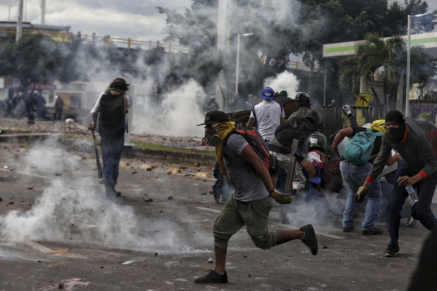 Protesters run from the tear gas during a national strike against tax reform in Cali, Colombia, Monday, May 3, 2021. Colombia's President Ivan Duque withdrew the government-proposed tax reform on Sunday. (AP Photo/Andres Gonzalez)