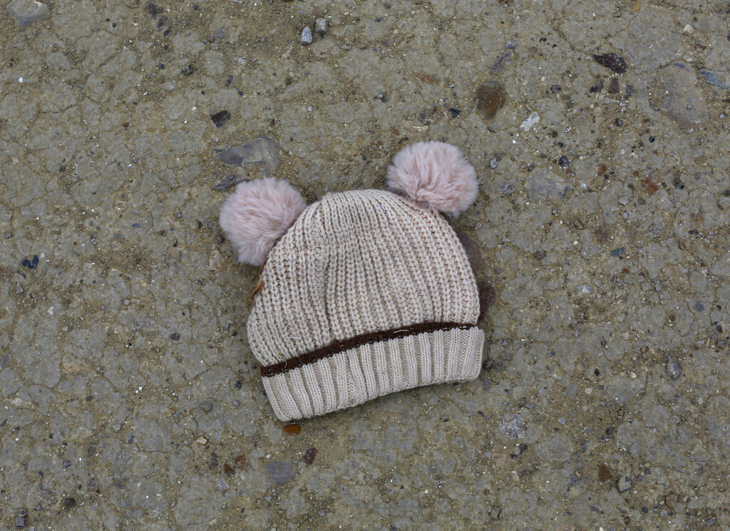 FILE - In this March 28, 2021, file photo, a child's knitted cap lies on the ground near the banks of the Rio Grande river in Roma, Texas. Confronted with a stream of unaccompanied children crossing the border from Mexico, the U.S. government has awarded shelter-construction and management contracts to private companies that critics say may not be equipped to adequately care for the minors. (AP Photo/Dario Lopez-Mills, File)