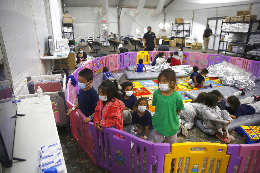 FILE - In this March 30, 2021, file photo, young unaccompanied migrants, watch television inside a playpen at the U.S. Customs and Border Protection facility, the main detention center for unaccompanied children in the Rio Grande Valley, in Donna, Texas. The number of unaccompanied children encountered on the U.S. border with Mexico in April 2021 eased from an all-time high a month earlier, while more adults were found coming without families, authorities said Tuesday., May 11, 2021. Authorities encountered 17,171 children traveling alone, down 9% from 18,960 in March, according to U.S. Customs and Border Protection, but still well above the previous high of 11,475 reported in May 2019 by the Border Patrol, which began publishing numbers in 2009. (AP Photo/Dario Lopez-Mills, Pool, File)
