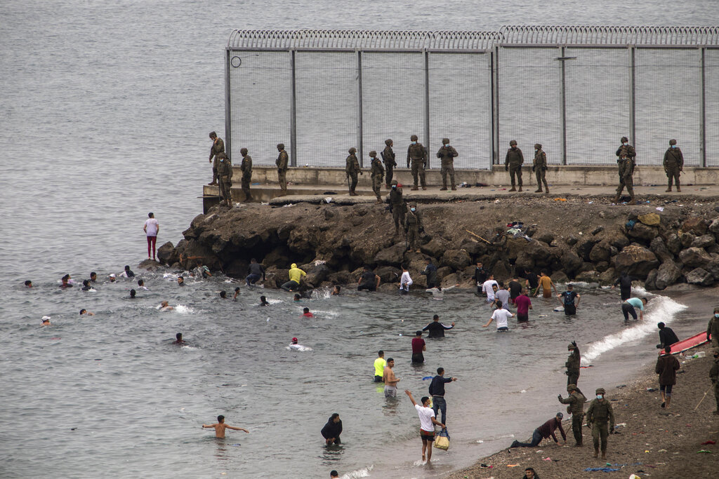 Spanish Army take positions as people from Morocco arrive swimming in the Spanish territory next to the border of Morocco and Spain, at the Spanish enclave of Ceuta, on Tuesday, May 18, 2021. Ceuta, a Spanish city of 85,000 in northern Africa, faces a humanitarian crisis after thousands of Moroccans took advantage of relaxed border control in their country to swim or paddle in inflatable boats into European soil. Around 6,000 people had crossed by Tuesday morning since the first arrivals began in the early hours of Monday, including 1,500 who are presumed to be teenagers. (AP Photo/Javier Fergo)