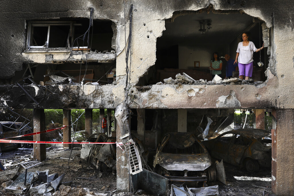 Members of Sror family inspect the damage of their apartment after it was hit by a rocket fired from the Gaza Strip over night in Petah Tikva, central Israel, Thursday, May 13, 2021. (AP Photo/Oded Balilty)