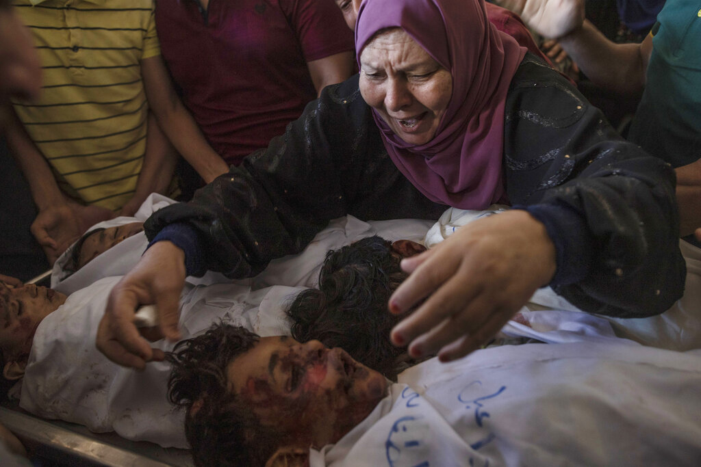 EDS NOTE: GRAPHIC CONTENT - A Palestinian relative mourns over the bodies of four brothers from the Tanani family who were found under the rubble of a destroyed house following Israeli airstrikes in Beit Lahiya, northern Gaza Strip, Friday, May 14, 2021. (AP Photo/Khalil Hamra)