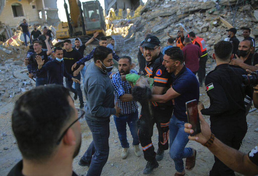EDS NOTE: GRAPHIC CONTENT - Palestinians carry the body of a child found in the rubble of a house belonging to the Tanani family, that was destroyed in Israeli airstrikes in the town of Beit Lahiya, northern Gaza Strip, Thursday, May 13, 2021. (AP Photo/Abdel Kareem Hana)