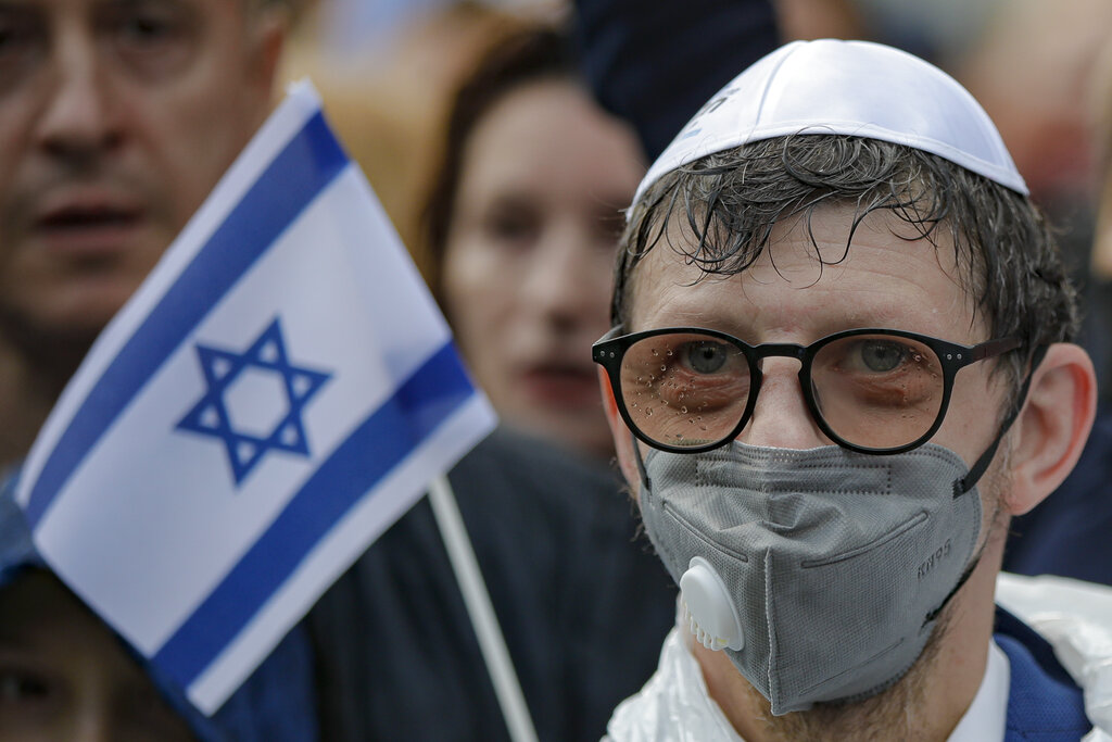 A man wears a face mask during a rally in support of Israel, joined by dozens, in Bucharest, Romania, Sunday, May 16, 2021. Israeli airstrikes on Gaza City flattened three buildings and killed at least 42 people Sunday, Palestinian medics said, in the deadliest single attack in the latest round of violence. (AP Photo/Vadim Ghirda)