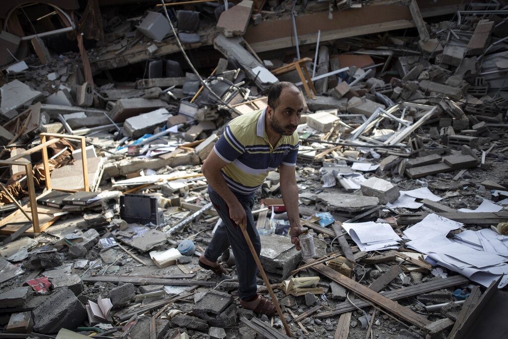 A Palestinian man inspects the damage of a house destroyed by an early morning Israeli airstrike, in Gaza City, Tuesday, May 18, 2021. Israel carried out a wave of airstrikes on what it said were militant targets in Gaza, leveling a six-story building in downtown Gaza City, and Palestinian militants fired dozens of rockets into Israel early Tuesday, the latest in the fourth war between the two sides, now in its second week. (AP Photo/Khalil Hamra)