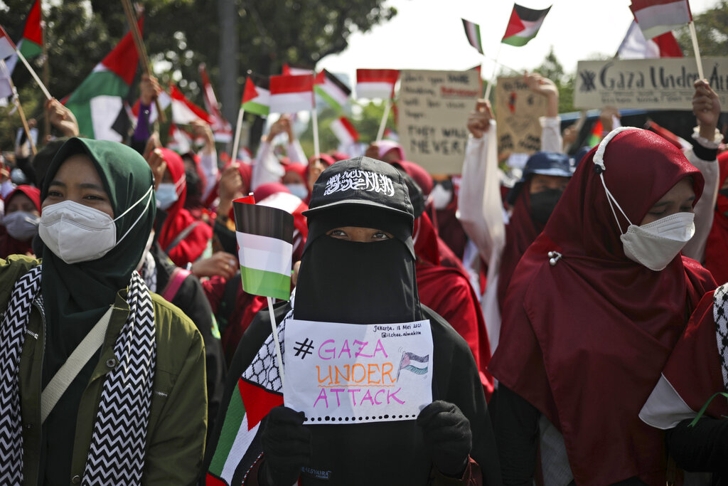 Muslim women display posters and wave Indonesian and Palestinian flags during an anti-Israel rally outside the U.S. Embassy in Jakarta, Indonesia, Tuesday, May 18, 2021. Pro-Palestinian protesters marched to the heavily guarded embassy on Tuesday to demand an end to Israeli airstrikes in the Gaza Strip. (AP Photo/Dita Alangkara)