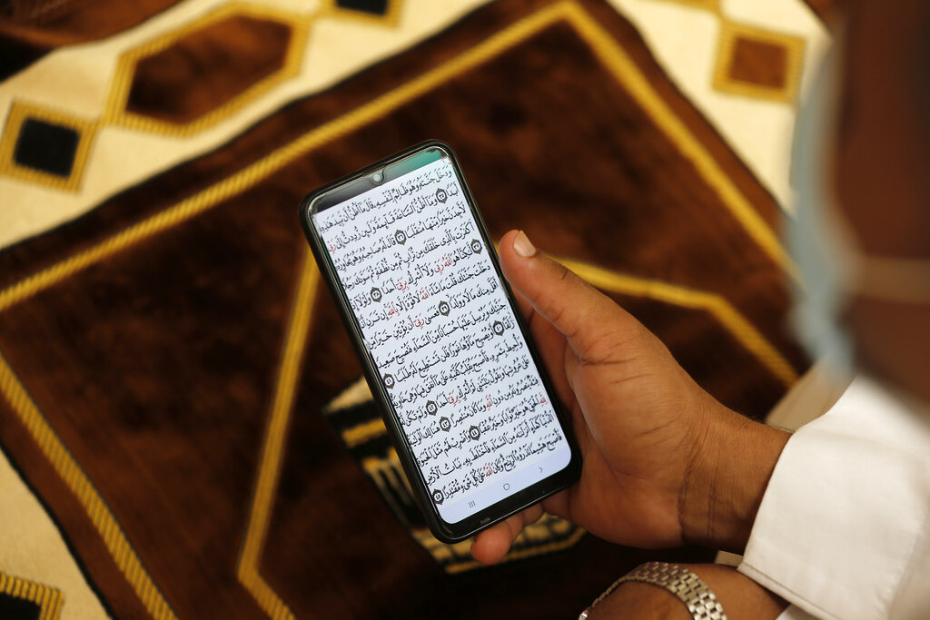 A Muslim worshipper reads verses of the Quran on his personal mobile phone to prevent the spread of coronavirus ahead of Friday prayer at Al- Jaffali mosque during the Muslim fasting month of Ramadan, in Jiddah, Saudi Arabia, Friday, April 30, 2021. (AP Photo/Amr Nabil)