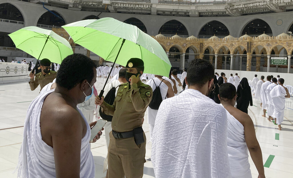 Saudi police watch Muslim pilgrims to ensure social distancing to help stop the spread of the coronavirus, as they circumambulate the Kaaba, during the minor pilgrimage, known as Umrah, at the Grand Mosque, in the Muslim holy city of Mecca, Saudi Arabia, Sunday, May 30, 2021.(AP Photo/Amr Nabil)