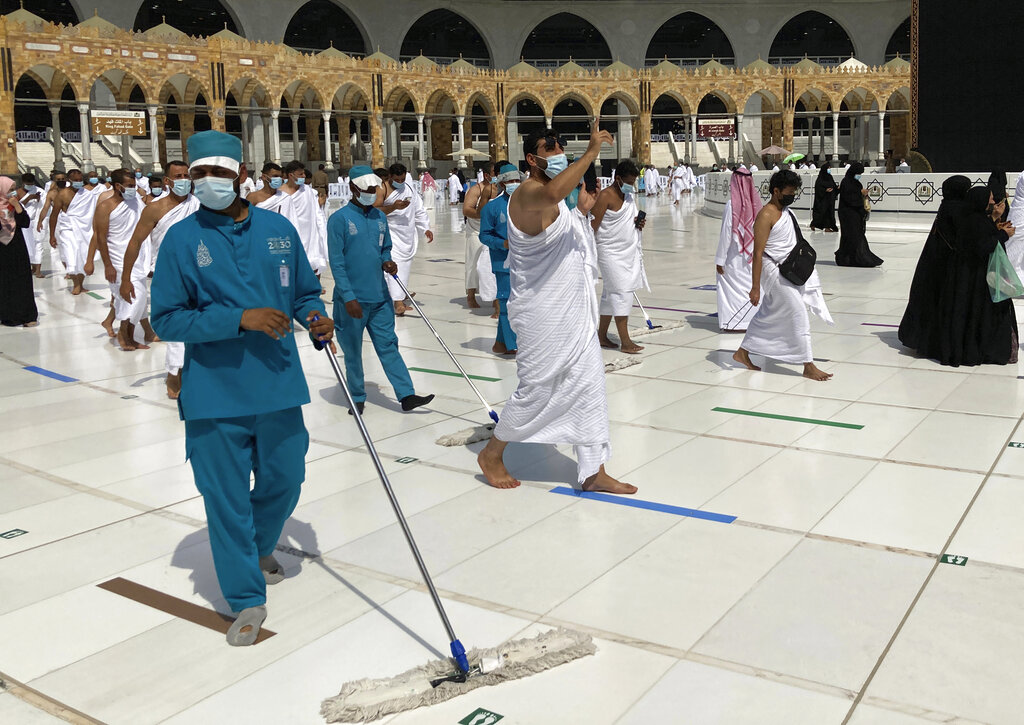 Workers disinfect the grounds as Muslim pilgrims circumambulate around the Kaaba, the cubic building at the Grand Mosque, during the minor pilgrimage, known as Umrah, at the Grand Mosque, in the Muslim holy city of Mecca, Saudi Arabia, Sunday, May 30, 2021. (AP Photo/Amr Nabil)