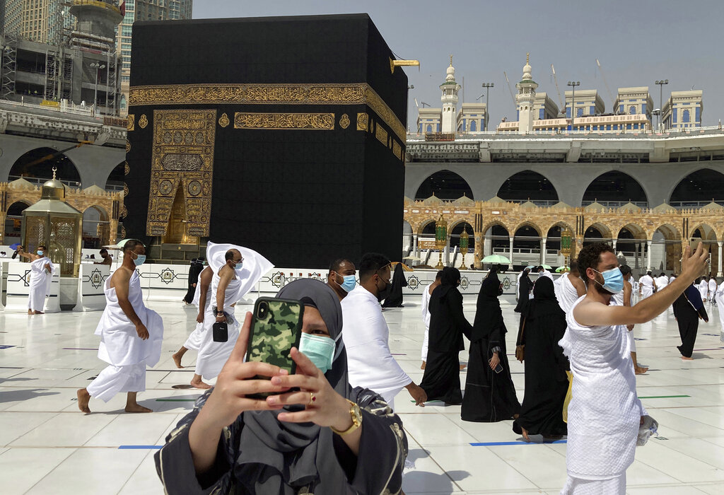 Muslim pilgrims wear face masks to help stop the spread of the coronavirus as they pose for selfies at the Grand Mosque in the Muslim holy city of Mecca, Saudi Arabia, Sunday, May 30, 2021. (AP Photo/Amr Nabil)
