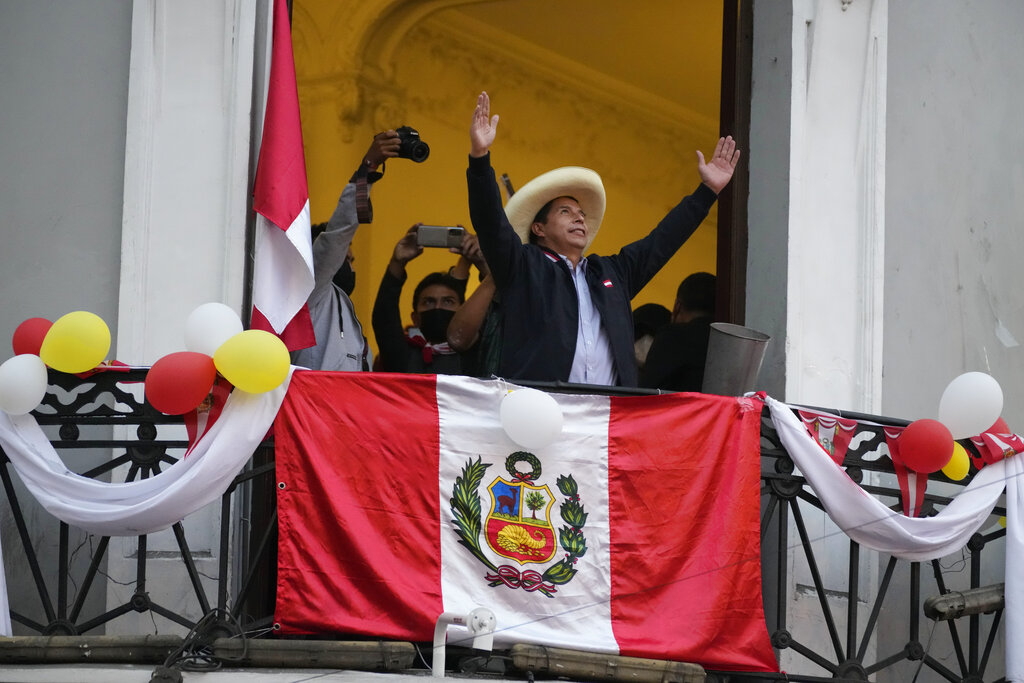 Presidential candidate Pedro Castillo greets supporters celebrating partial election results that show him leading over Keiko Fujimori, at his campaign headquarters in Lima, Peru, Monday, June 7, 2021, the day after a runoff election. (AP Photo/Martin Mejia)