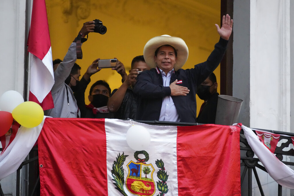 Presidential candidate Pedro Castillo waves to supporters celebrating partial election results that show him leading over Keiko Fujimori, at his campaign headquarters in Lima, Peru, Monday, June 7, 2021, the day after a runoff election. (AP Photo/Martin Mejia)