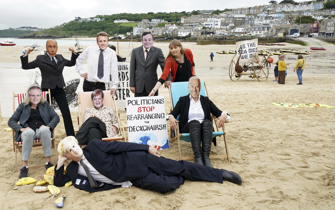 Activists pose with faces of the G7 and other world leaders as they demonstrate on the beach in the harbour near the G7 meeting taking place in St. Ives, Cornwall, England, Friday, June 11, 2021. Leaders of the G7 begin their first of three days of meetings on Friday in Carbis Bay, in which they will discuss COVID-19, climate, foreign policy and the economy. Leaders faces from left, Australia's Prime Minister Scott Morrison, Russian President Vladimir Putin, British Prime Minister Boris Johnson, French President Emmanuel Macron, German Chancellor Angela Merkel, Italy's Prime Minister Mario Draghi and U.S. President Joe Biden. (AP Photo/Jon Super)
