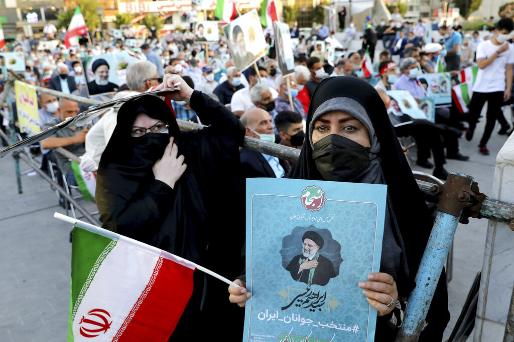 Supporters of presidential candidate Ebrahim Raisi hold signs and the Iranian flag during a rally in Tehran, Iran, Monday, June 14, 2021. Iran's clerical vetting committee has allowed just seven candidates for the Friday, June 18, ballot, nixing prominent reformists and key allies of President Hassan Rouhani. The presumed front-runner has become Ebrahim Raisi, the country's hard-line judiciary chief who is closely aligned with Supreme Leader Ayatollah Ali Khamenei. (AP Photo/Ebrahim Noroozi)