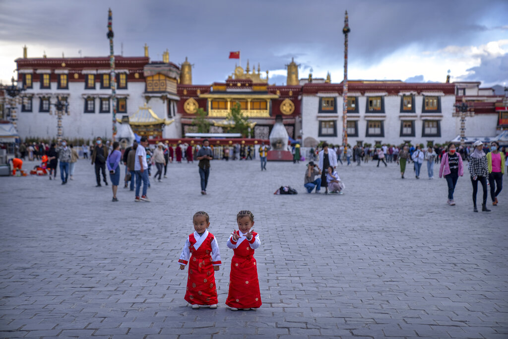 Girls stand on a square in front of the Jokhang Temple in Lhasa in western China's Tibet Autonomous Region, as seen during a government organized visit for foreign journalists, Tuesday, June 1, 2021. (AP Photo/Mark Schiefelbein)