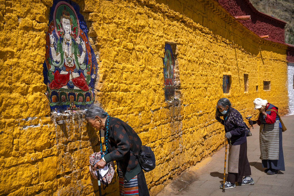 Members of the Buddhist faithful pray outside the Potala Palace in Lhasa in western China's Tibet Autonomous Region, as seen during a government organized visit for foreign journalists, Tuesday, June 1, 2021. (AP Photo/Mark Schiefelbein)