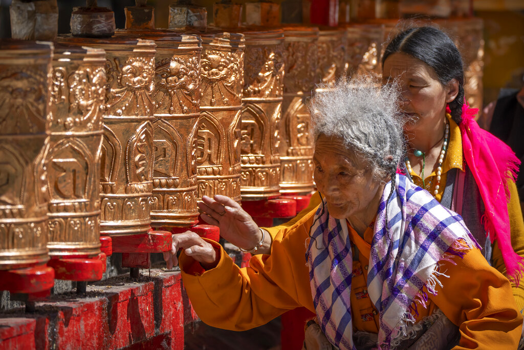 Members of the Buddhist faithful spin prayer wheels outside the Potala Palace in Lhasa in western China's Tibet Autonomous Region, as seen during a government organized visit for foreign journalists, Tuesday, June 1, 2021. (AP Photo/Mark Schiefelbein)