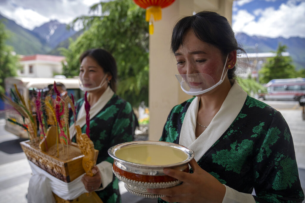 Hostesses hold items to welcome guests during a government organized visit for foreign journalists in Gongbujiangda County in Nyingchi in western China's Tibet Autonomous Region, Thursday, June 3, 2021. (AP Photo/Mark Schiefelbein)
