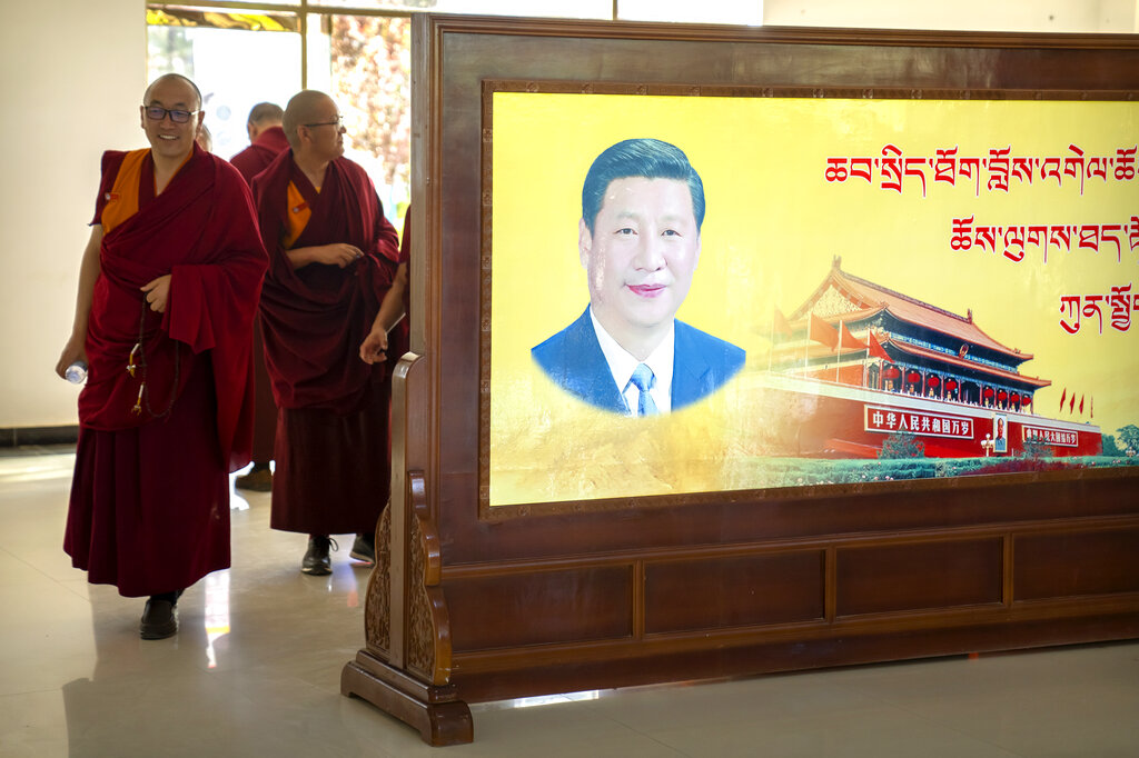 Monks walk past a mural with a portrait of Chinese President Xi Jinping and the Tiananmen Gate at the Tibetan Buddhist College near Lhasa in western China's Tibet Autonomous Region, Monday, May 31, 2021, as seen during a government organized visit for foreign journalists. High-pressure tactics employed by China's ruling Communist Party appear to be finding success in separating Tibetans from their traditional Buddhist culture and the influence of the Dalai Lama. (AP Photo/Mark Schiefelbein)