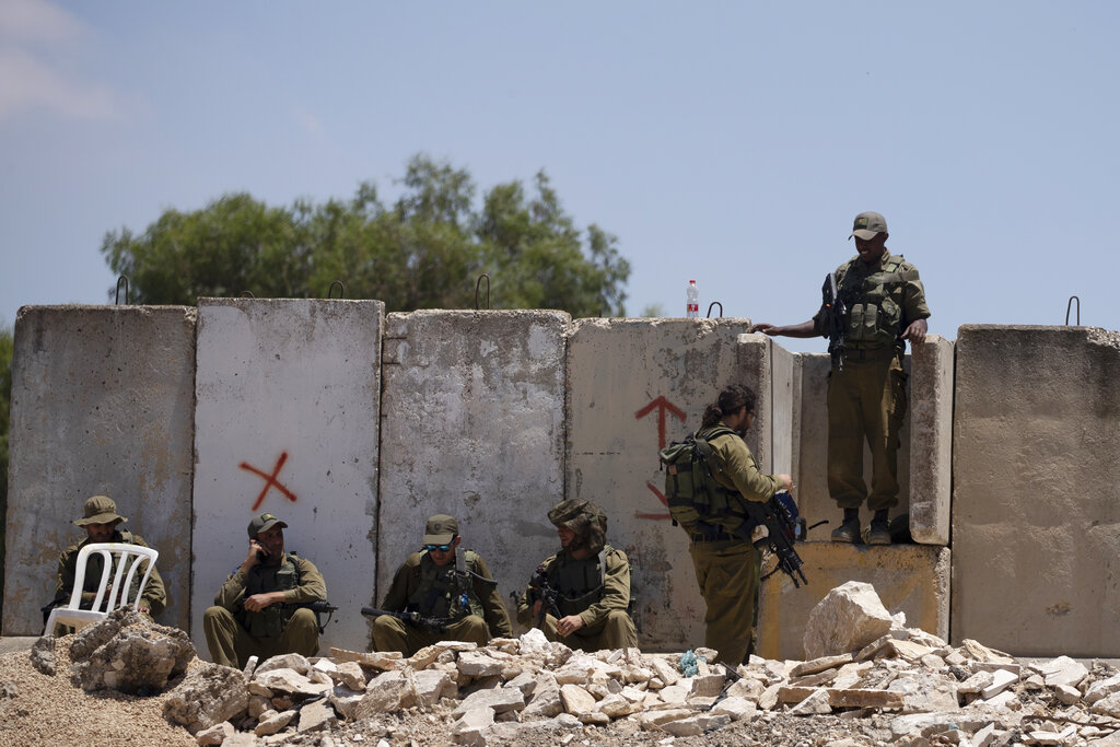 Israeli soldiers rest at the site of a vehicle attack near Hizmeh Junction in the West Bank, Wednesday, June 16, 2021. The Israeli military on Wednesday shot and killed a Palestinian woman who it said tried to ram her car into a group of soldiers guarding a West Bank construction site. (AP Photo/Maya Alleruzzo)