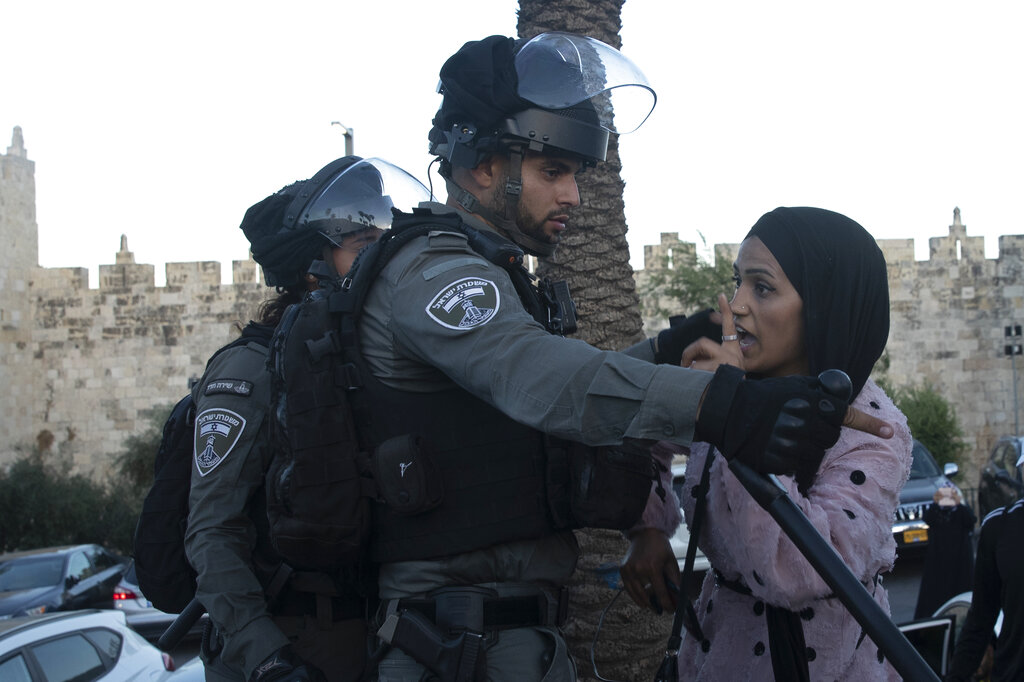 An Israeli border police officer faces off with a Palestinian woman at a protest at the Damascus Gate to the Old City of Jerusalem Thursday, June 17, 2021 against incendiary chants used by ultranationalist Israelis at their 