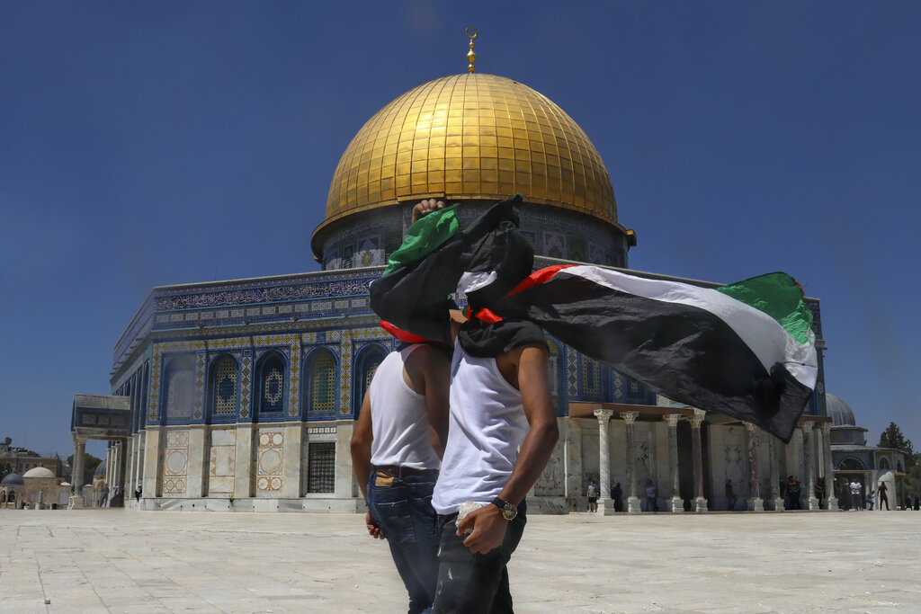 Masked Palestinians wearing the Palestinian flag during clashes with Israeli security forces in front of the Dome of the Rock Mosque at the Al Aqsa Mosque compound in Jerusalem's Old City, Friday, June 18, 2021. Hundreds demonstrated after Friday prayers in response to a rally held by Jewish ultranationalists on Tuesday in which dozens had chanted 