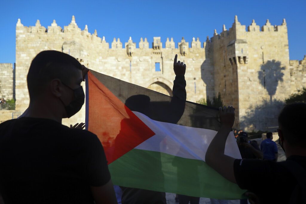 FILE - In this June 19, 2021, file photo, Palestinians demonstrators wave the Palestinian flag during protest in Damascus gate just outside Jerusalem's Old City. Palestinians and Jewish settlers hurled stones, chairs and fireworks at each other overnight in a tense Jerusalem neighborhood where settler groups are trying to evict several Palestinian families, officials said Tuesday, June 22. (AP Photo/Mahmoud Illean, File)