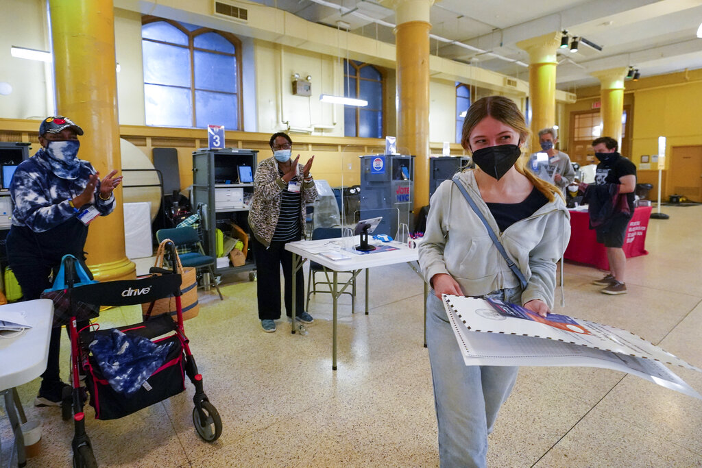 Election workers applaud as June Harkrider, who turned 18 in March, walks to the privacy booth to vote for the first time during early voting in the primary election, Monday, June 14, 2021, at the Church of St. Anthony of Padua in the Soho neighborhood of New York. (AP Photo/Mary Altaffer)