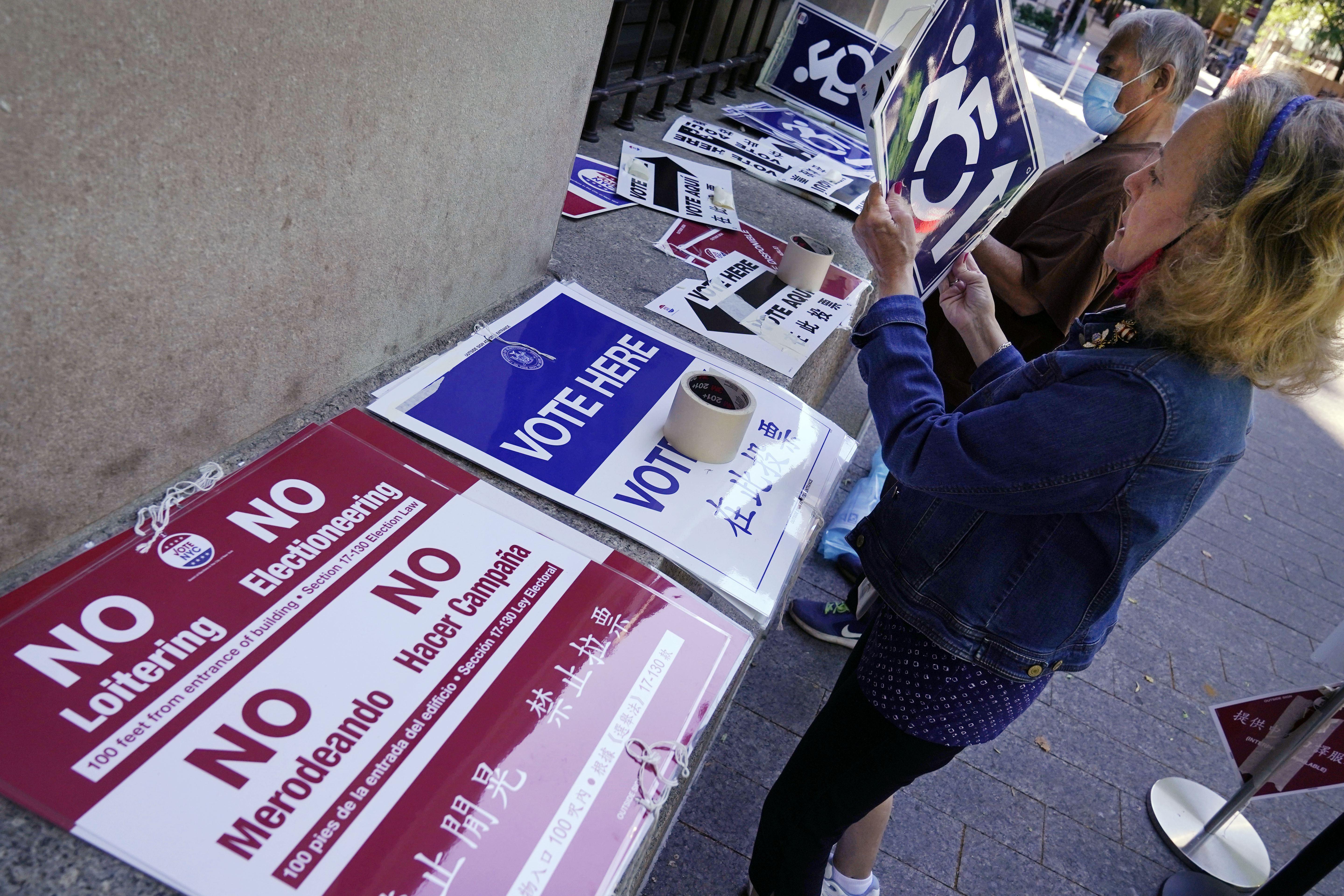 A worker prepares direction signs outside the early voting site at the Metropolitan Museum of Art, in New York, Thursday, June 17, 2021. (AP Photo/Richard Drew)