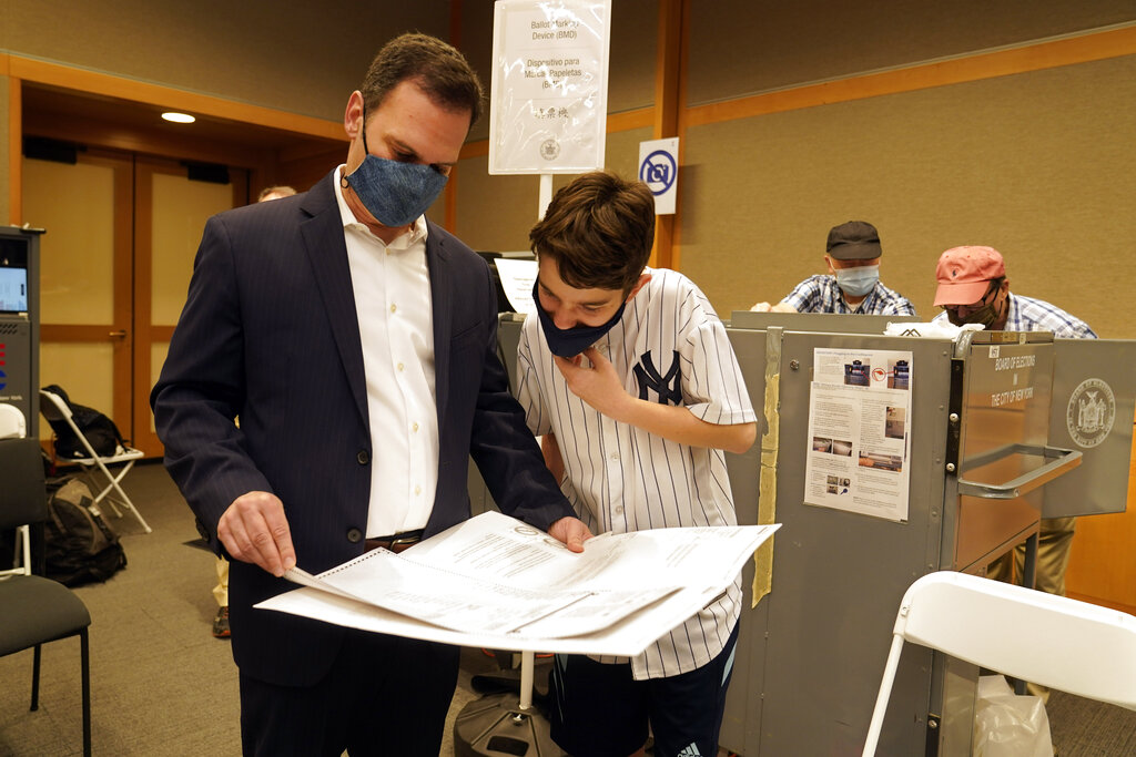 New York State Assembly member, and candidate for Manhattan district attorney, Dan Quart, and his son Sam, look at his ballot at an early voting site at the Metropolitan Museum of Art, in New York, Thursday, June 17, 2021. (AP Photo/Richard Drew)