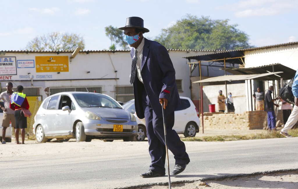 An elderly man, wearing a mask to protect against COVID-19 walks at a rural shopping center in Zvimba, Zimbabwe Friday, June 25, 2021. A new surge of the coronavirus is finally penetrating Africa’s rural areas, where most people on the continent live, spreading to areas that once had been seen as safe havens from infections that hit cities particularly hard. (AP Photo/Tsvangirayi Mukwazhi)