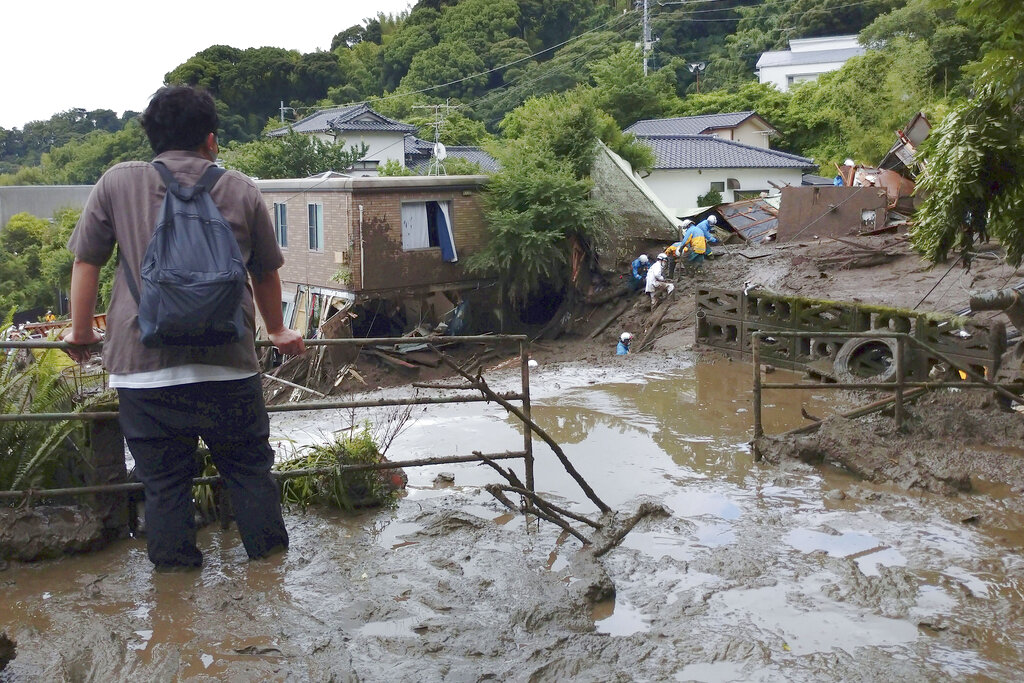A man watches as rescuers continue a search operation at the site of a mudslide at Izusan in Atami, Shizuoka prefecture, southwest of Tokyo Monday, July 5, 2021. (Kyodo News via AP)
