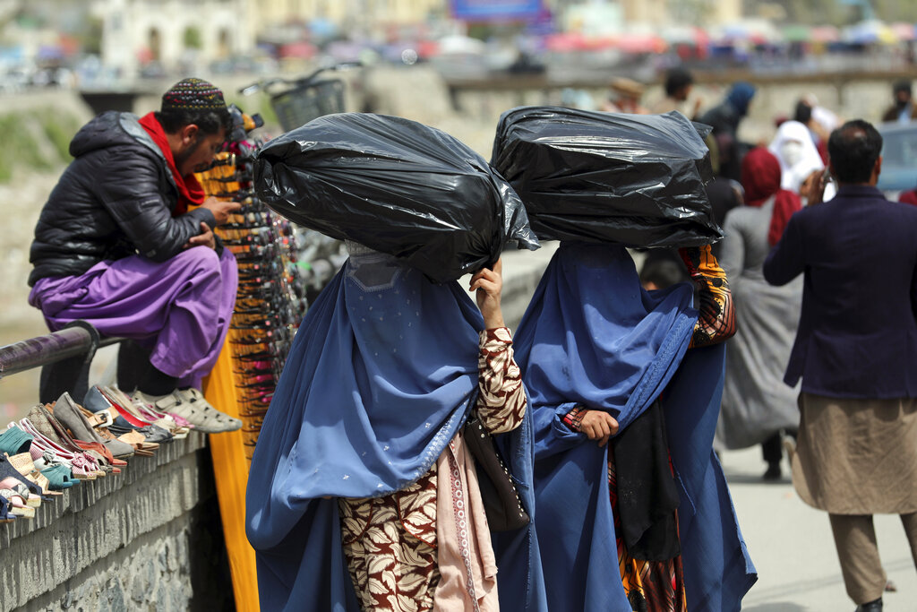 FILE - In this April 7, 2021 file photo, women carry sacks of goods in a street market in Kabul, Afghanistan. Afghanistan remains one of the worst countries in the world for women, after only Yemen and Syria, according to an index kept by Georgetown University’s Institute for Women, Peace and Security. (AP Photo/Rahmat Gul, File)