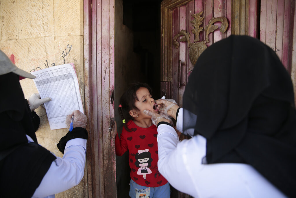 A Yemeni health worker gives the polio vaccination to a girl during a house-to-house polio immunization campaign in Sanaa, Yemen, Sunday, May 30, 2021. (AP Photo/Hani Mohammed)