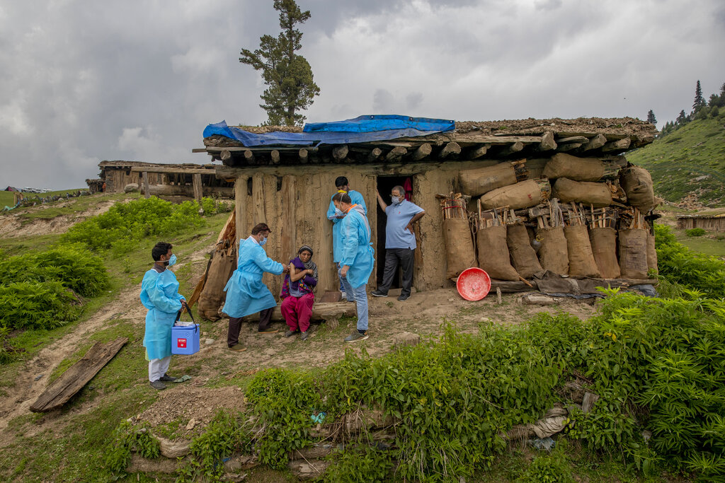Dr Tajamul Hussain Khan, chief medical officer, right, watches as a healthcare worker from his team administers a dose of Covishield vaccine to Saja Begum outside her hut during a vaccination drive in Tosamaidan, southwest of Srinagar, Indian controlled Kashmir on June 21, 2021. (AP Photo/Dar Yasin)