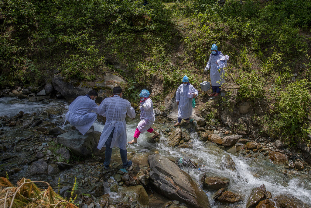 A team of health workers cross a stream to reach the villages on the upper reaches during a COVID-19 vaccination drive in Gund, northeast of Srinagar, Indian controlled Kashmir, on June 22, 2021. The challenge for health workers travelling to to long distances for vaccinating mostly shepherds and nomadic herders in the remote meadows of the Himalayan region has not been the treacherous terrain but to persuade women to get COVID-19 vaccines. Fueled by misinformation and mistrust, many residents, particularly in remote rural areas, believe that vaccines cause impotence, serious side effects and could even kill. Some simply say they do not need the shots because they’re immune to the coronavirus. (AP Photo/Dar Yasin)
