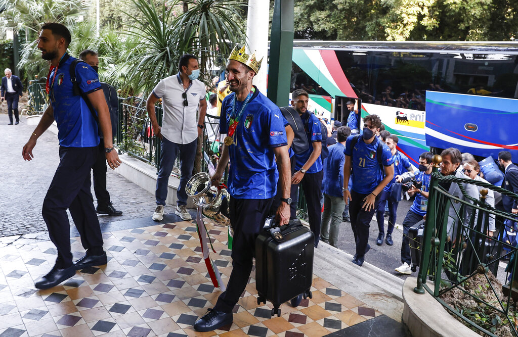 Italy's captain Giorgio Chiellini, wearing a crown and holding the trophy, and his teammates arrive at a hotel after returning from London, in Rome, Monday, July 12, 2021. Italy defeated England 3-2 in a penalty shootout after a 1-1 draw, to win the Euro 2020 soccer championships in a final played at Wembley stadium in London on July 11. (AP Photo/Riccardo De Luca)