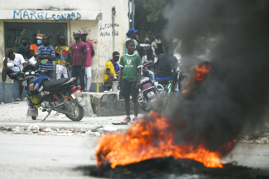 In this July 12, 2021, photo, a tire set on fire by supporters of former Senators Youri Latortue and Steven Benoit outside the courthouse in Port-au-Prince. The problems of two tiny Caribbean states, Cuba and Haiti, have vexed U.S. presidents for decades. Now, Haiti and Cuba are posing a growing challenge for President Joe Biden that could have political ramifications. (AP Photo/Matias Delacroix)