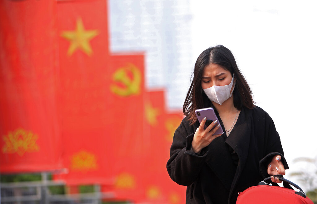 In this Jan. 23, 2021, file photo, a woman wearing face mask looks at her phone in Hanoi, Vietnam. Amnesty International has found that a hacking group known as Ocean Lotus has been staging more spyware attacks on Vietnamese human rights activists in the latest blow to freedom of speech in the communist-ruled country. (AP Photo/Hau Dinh, File)