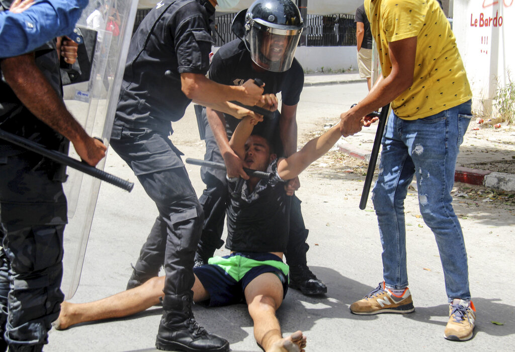 Tunisian police officers detain a protester during a demonstration in Tunis, Tunisia, Sunday, July 25, 2021. Violent demonstrations broke out on Sunday in several Tunisian cities as protesters expressed anger at the deterioration of the country's health, economic and social situation. (AP Photo/Hassene Dridi)