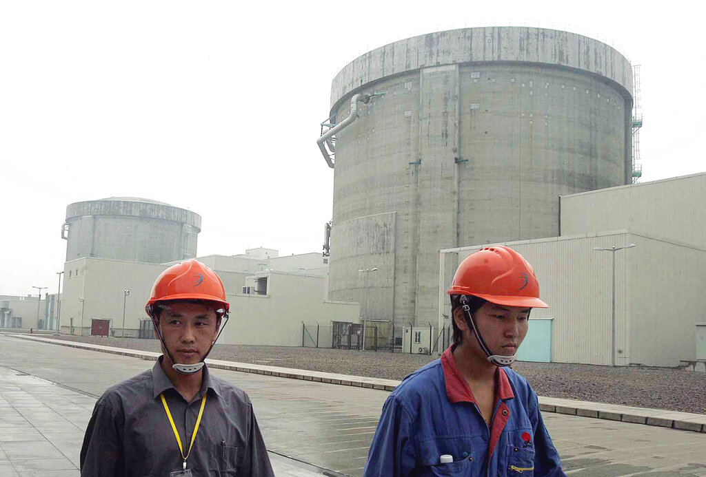 FILE - In this June 10, 2005 file photo, workers walk past a part of the Qinshan No. 2 Nuclear Power Plant, China's first self-designed and self-built national commercial nuclear power plant in Qinshan, about 125 kilometers (about 90 miles) southwest of Shanghai, China. Beijing's wants to compete with the United States, France and Russia as an exporter of atomic power technology. (AP Photo/Eugene Hoshiko, File)