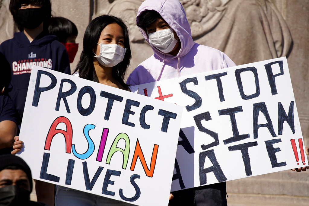 FILE - This March 20, 2021, file photo shows people holding signs as they attend a rally to support Stop Asian Hate at the Logan Square Monument in Chicago. A national coalition of civil rights groups will release on Wednesday, July 28, 2021, a comprehensive, state-by-state review of hate crime laws in the United States. Members of the coalition say the report sets the stage for bolstering the efficacy of current law and addresses racial disparities in how the laws are enforced. (AP Photo/Nam Y. Huh, File)