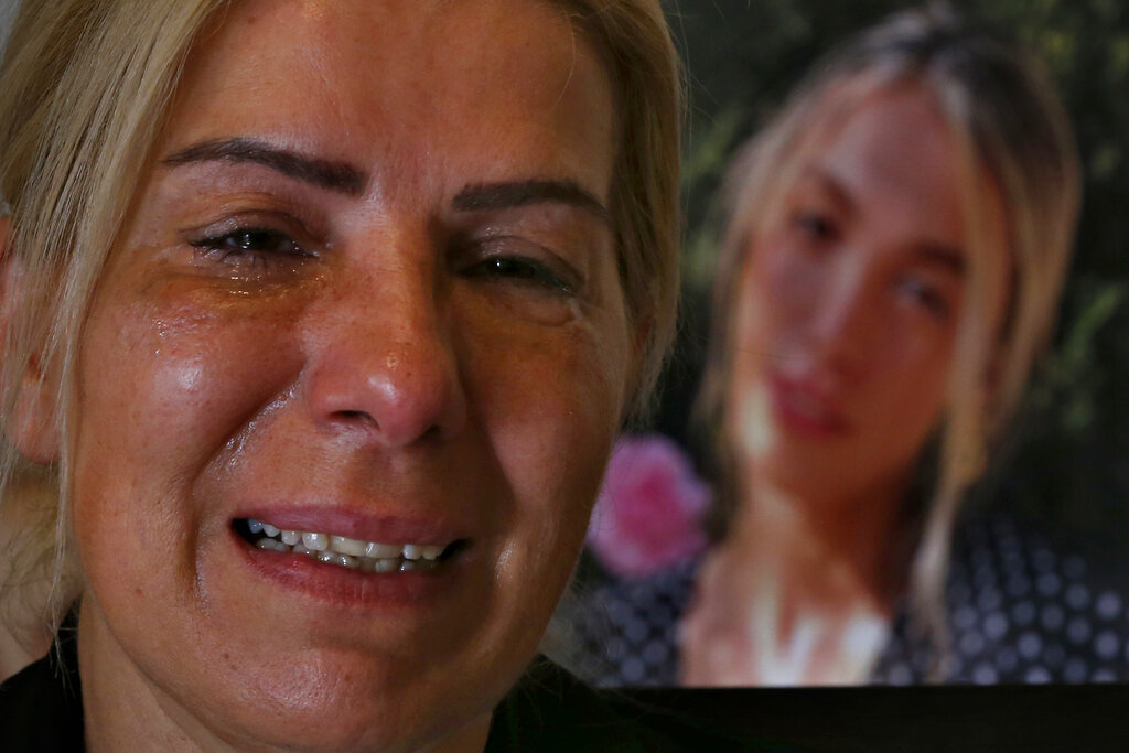 Chouchan Yeghiyan weeps in front of a picture of her daughter, Jessica Bezdjian, who was killed in last year's massive blast at Beirut's seaport, during an interview with The Associated Press at her home in Antelias, Lebanon, Monday, July 12, 2021. Bezidjian was one of four female nurses who lost their lives at the Saint George Hospital University Medical Center that day, including her close friend Jessica Kahwaji who was instantly killed. (AP Photo/Bilal Hussein)