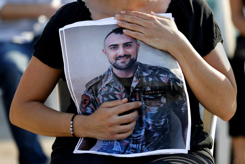 A relative of a firefighter who was killed in the massive blast last year at the Beirut port hugs his portrait as she attends a mass held to commemorate the first year anniversary of the deadly blast, at the Beirut port, Lebanon, Wednesday, Aug. 4, 2021.  (AP Photo/Hussein Malla)