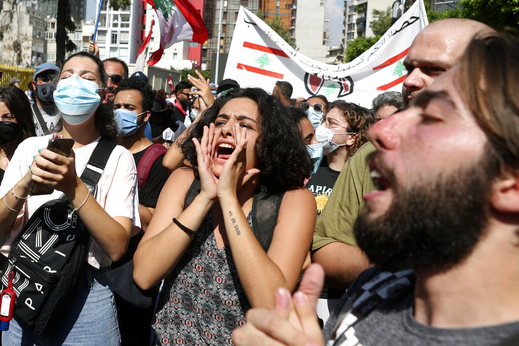 Anti-government protesters chant slogans during a protest marking the first anniversary of the massive blast at Beirut's port, in Beirut, Lebanon, Wednesday, Aug. 4, 2021.  The grim anniversary comes amid an unprecedented economic and financial meltdown and a political stalemate that has kept the country without a functioning government for a full year. (AP Photo/Bilal Hussein)