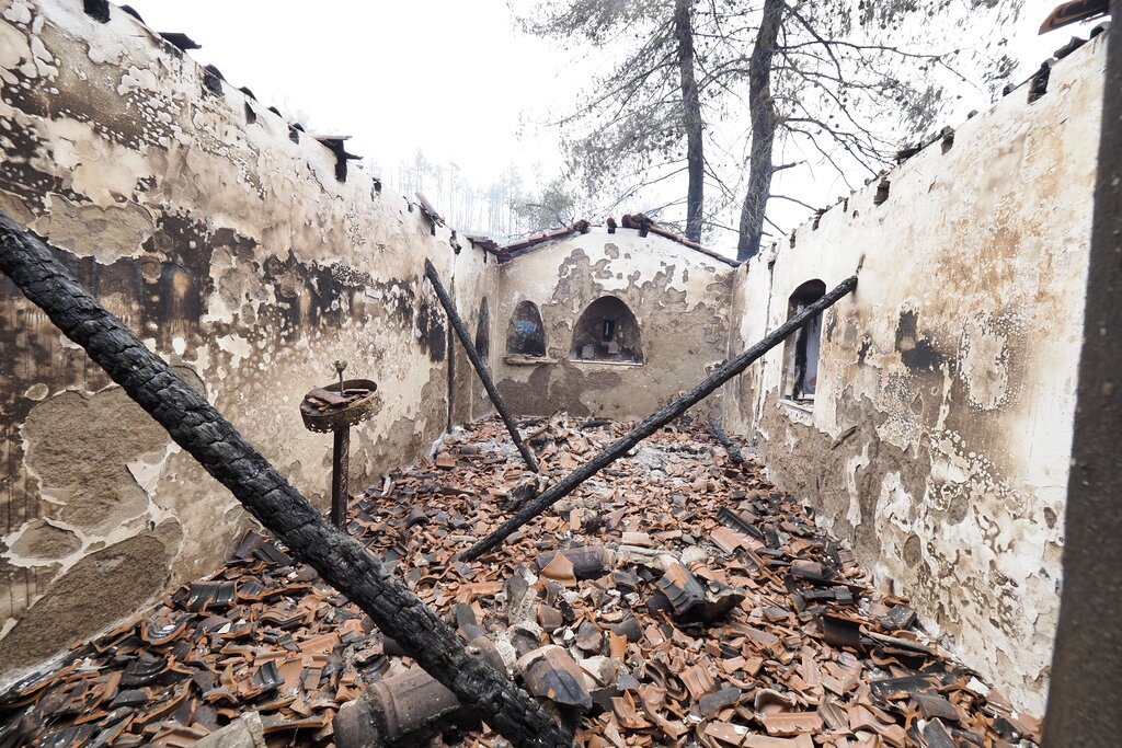 A burnt Greek Orthodox chapel during a wildfire in Kirinthos village on the island of Evia, about 135 kilometers (84 miles) north of Athens, Greece, Friday, Aug. 6, 2021. Thousands of people fled wildfires burning out of control in Greece and Turkey on Friday, including a major blaze just north of the Greek capital of Athens that claimed one life, as a protracted heat wave left forests tinder-dry and flames threatened populated areas and electricity installations. (AP Photo/Thodoris Nikolaou)