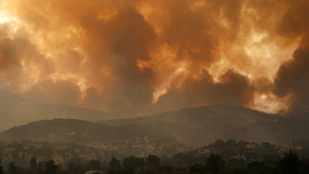 Smoke spreads over Parnitha mountain during a wildfire in Ippokratios Politia village, about 35 kilometres (21 miles), northern Athens, Greece, Friday, Aug. 6, 2021. Thousands of people fled wildfires burning out of control in Greece and Turkey on Friday, including a major blaze just north of the Greek capital of Athens that claimed one life, as a protracted heat wave left forests tinder-dry and flames threatened populated areas and electricity installations. (AP Photo/Lefteris Pitarakis)