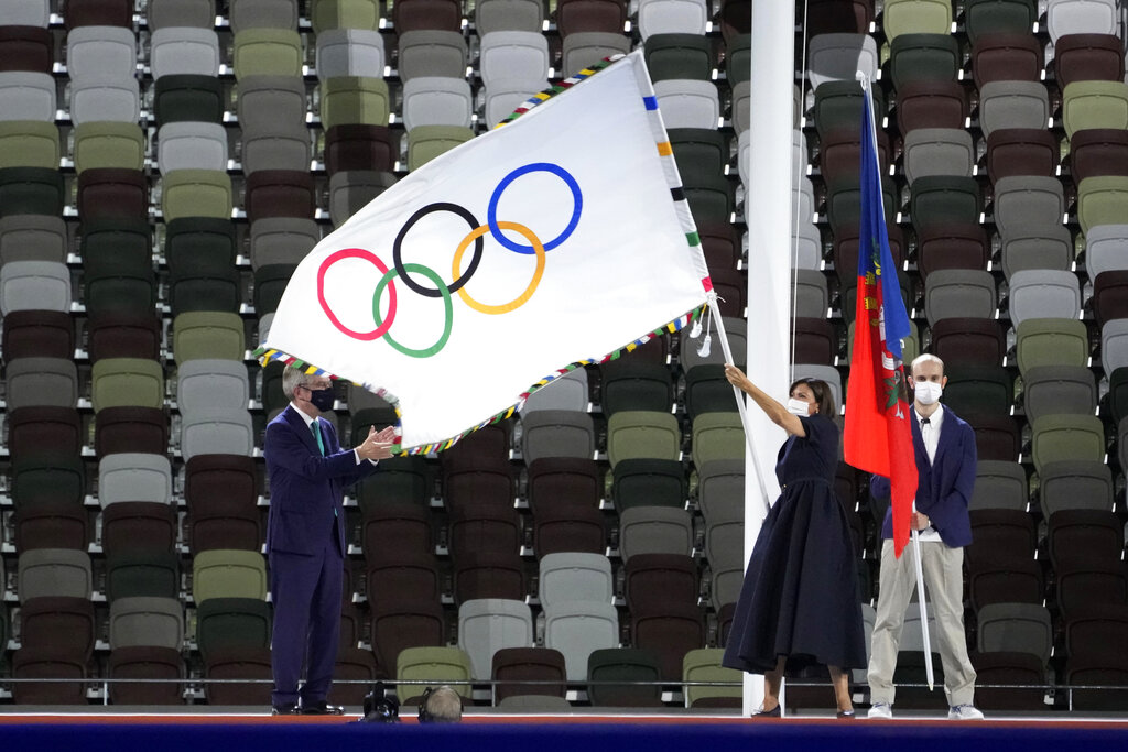 Anne Hidalgo, Mayor of Paris, holds the Olympian flag while International Olympic Committee's President Thomas Bach stands at left during the closing ceremony in the Olympic Stadium at the 2020 Summer Olympics, Sunday, Aug. 8, 2021, in Tokyo, Japan. (AP Photo/David Goldman)
